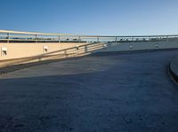 a skate board is leaning against the wall next to an asphalt parking lot with a blue sky