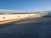 a skate board is leaning against the wall next to an asphalt parking lot with a blue sky