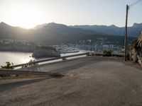 there is a truck parked at the end of a hill next to water and mountains