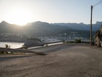 there is a truck parked at the end of a hill next to water and mountains