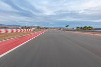 a photo of a dirt race track with sun setting in the distance of the track