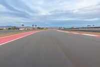 a photo of a dirt race track with sun setting in the distance of the track