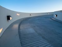 curved stairs are lined around an outside building with bright lights on the walls and cement ground