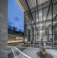 a room with a glass entrance and a round rock at night in the courtyard area