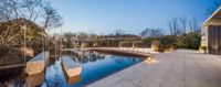 a backyard with an artificial pond, gazebo and seating areas and wooden furniture and table setting