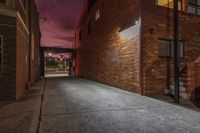 a red brick building with a window near a parking lot under a cloudy sky at night