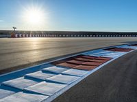 a photo of a dirt race track with sun setting in the distance of the track