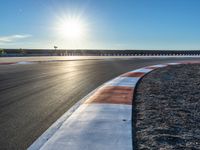 a photo of a dirt race track with sun setting in the distance of the track