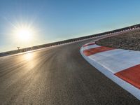 a photo of a dirt race track with sun setting in the distance of the track