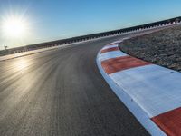 a photo of a dirt race track with sun setting in the distance of the track