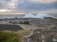 a surfer stands on the rock by the water's edge as waves crash against the rocks