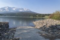 there is a dock next to a lake with mountains in the background and water below