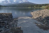 there is a dock next to a lake with mountains in the background and water below