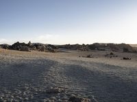 the sun is setting behind the barren landscape with rocks and debris in the foreground