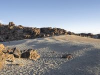 some rock formations on a hill and some dirt ground with large rocks in the background