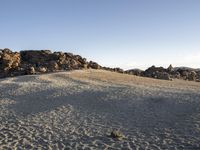 some rock formations on a hill and some dirt ground with large rocks in the background