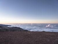 a man stands at the top of the mountain with his legs in the air with clouds below him