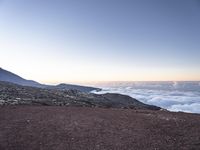 a man stands at the top of the mountain with his legs in the air with clouds below him