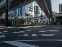 an empty road with a street sign at the curb in front of an office building