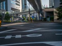 an empty road with a street sign at the curb in front of an office building