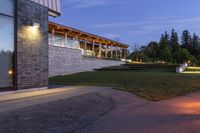 the house is outside, facing the water and on the grass lawn with illuminated lights