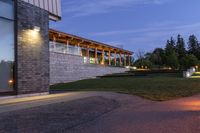 the house is outside, facing the water and on the grass lawn with illuminated lights