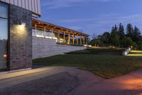 the house is outside, facing the water and on the grass lawn with illuminated lights