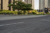 an empty street with many tall buildings in the background and a small white truck is on the right corner