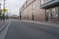 an empty street with a yellow sign on the road and an empty building on the side