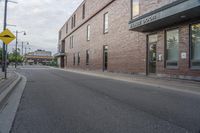 an empty street with a yellow sign on the road and an empty building on the side