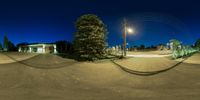 the street is empty and has the lights on and a street light above it,