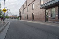 the building is brick with lots of windows, and there is a sidewalk on which to park and walk