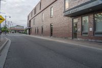 the building is brick with lots of windows, and there is a sidewalk on which to park and walk