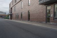 the building is brick with lots of windows, and there is a sidewalk on which to park and walk