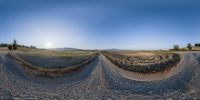 360 camera view of a long road in the distance with a sun rising over the mountains