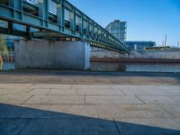 a skateboarder riding on a cement ramp next to a city street under a bridge