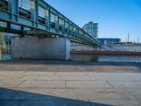 a skateboarder riding on a cement ramp next to a city street under a bridge