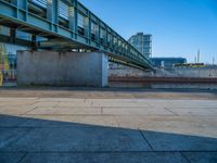 a skateboarder riding on a cement ramp next to a city street under a bridge