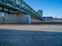 a skateboarder riding on a cement ramp next to a city street under a bridge