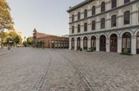 a row of buildings with arches and arched doors are lined up along an empty cobblestone road