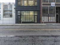 an empty street in front of a black building with two doors that look like they are standing on the corner
