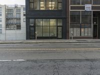 an empty street in front of a black building with two doors that look like they are standing on the corner