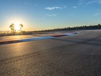 a photo of a dirt race track with sun setting in the distance of the track