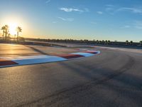 a photo of a dirt race track with sun setting in the distance of the track