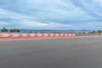 a photo of a dirt race track with sun setting in the distance of the track