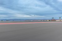 a photo of a dirt race track with sun setting in the distance of the track