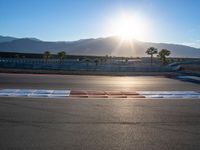 a photo of a dirt race track with sun setting in the distance of the track