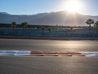 a photo of a dirt race track with sun setting in the distance of the track