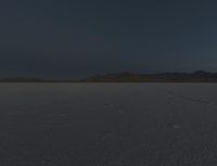 a lone motorcycle is on a barren plain under a cloudy sky in the middle of nowhere