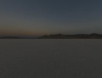 a lone motorcycle is on a barren plain under a cloudy sky in the middle of nowhere